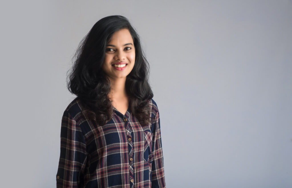 portrait of a young beautiful cute cheerful girl smiling looking at the camera on gray background
